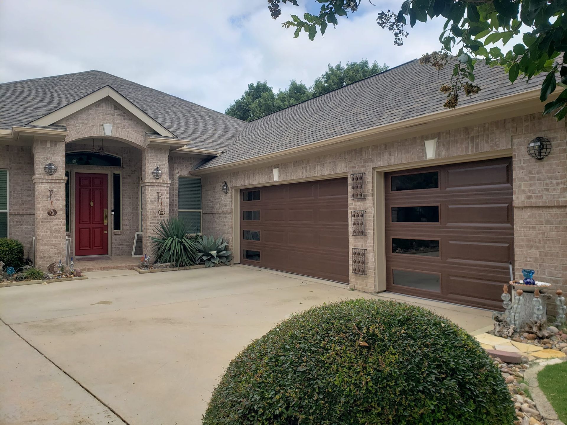 Brick house with brown garage doors and a red front door.