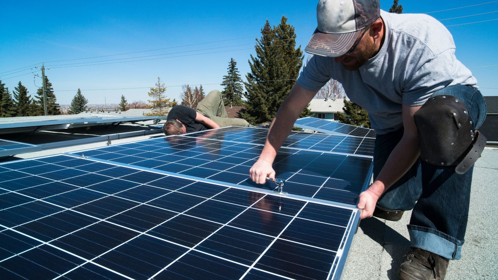 A man is installing solar panels on the roof of a building.
