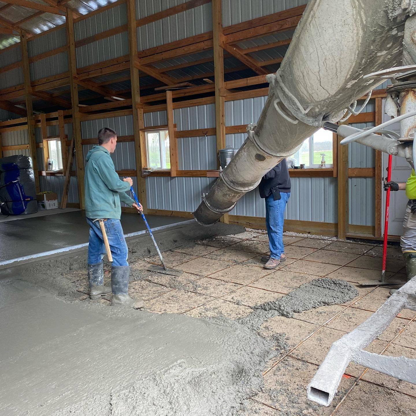Concrete being poured into a barn floor; workers use tools to smooth the surface.