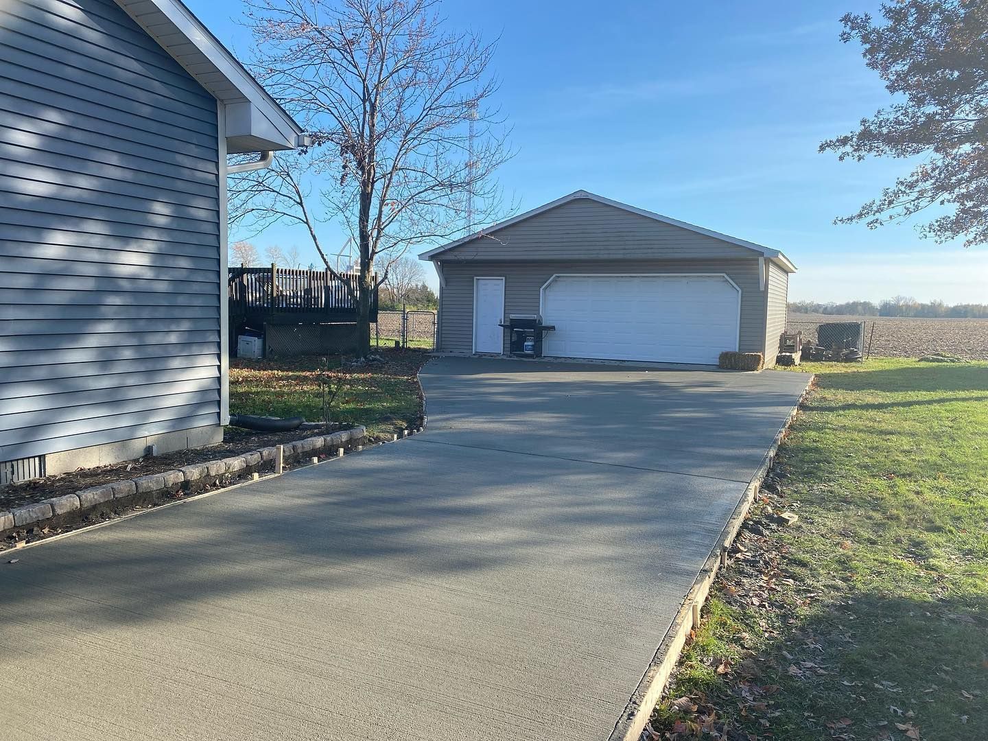 Driveway leading to a detached garage and house on a sunny day.