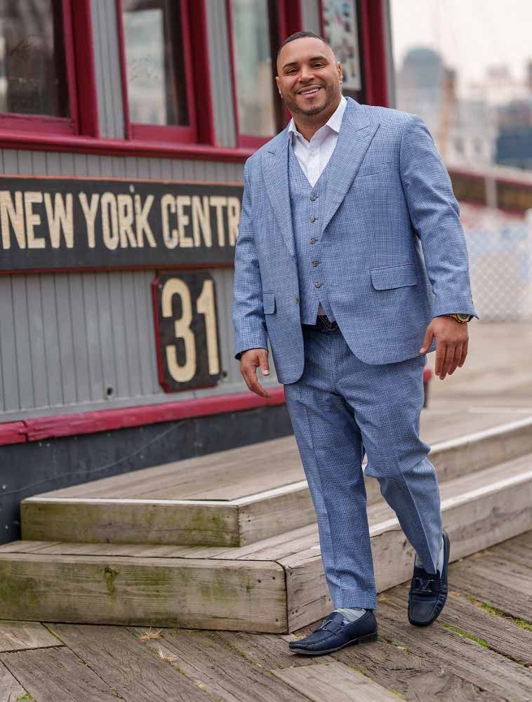 Man in blue suit, smiling, walking on wooden steps near
