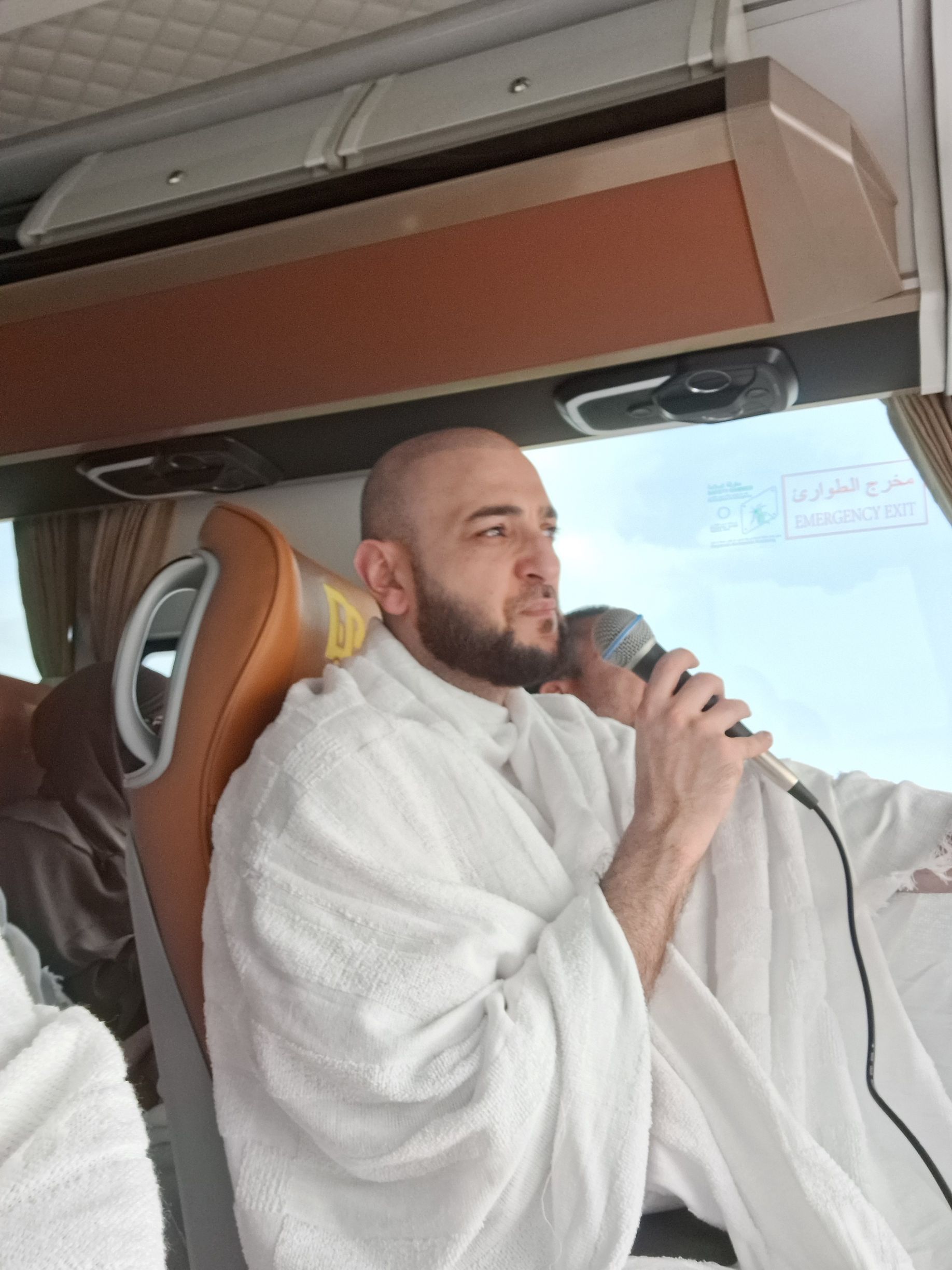 Een man met een baard zingt in een microfoon in een bus