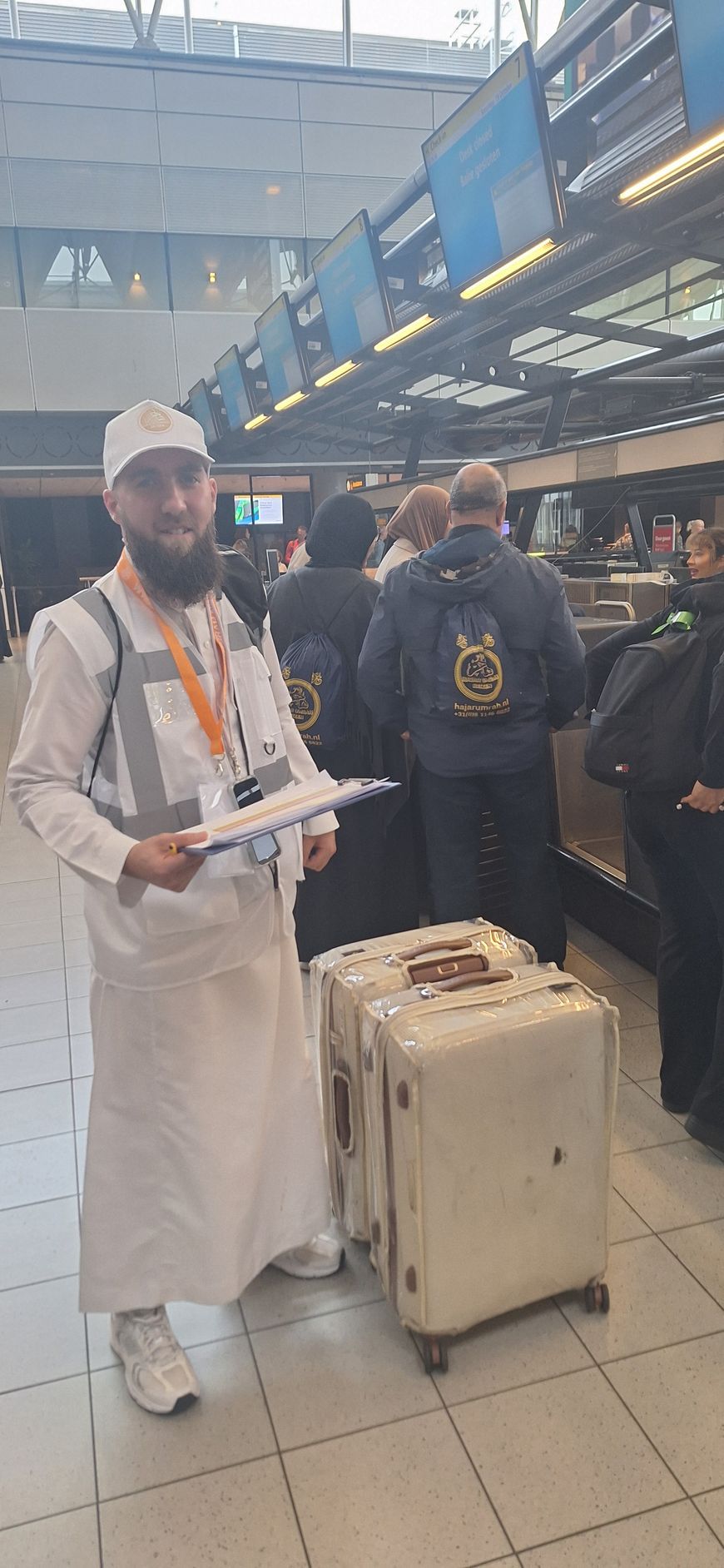 Een man met een baard staat op een vliegveld met bagage.