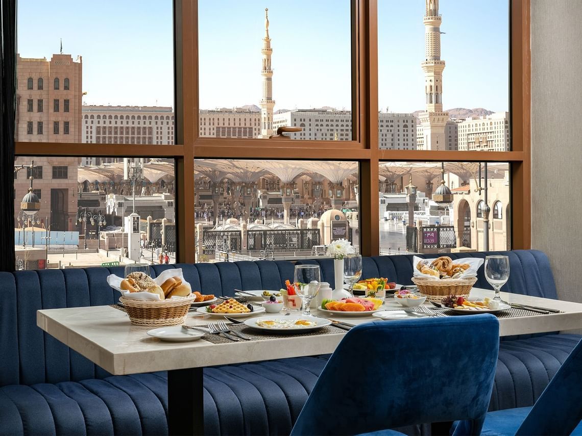 Een restaurant met een tafel, stoelen en uitzicht op de stad.