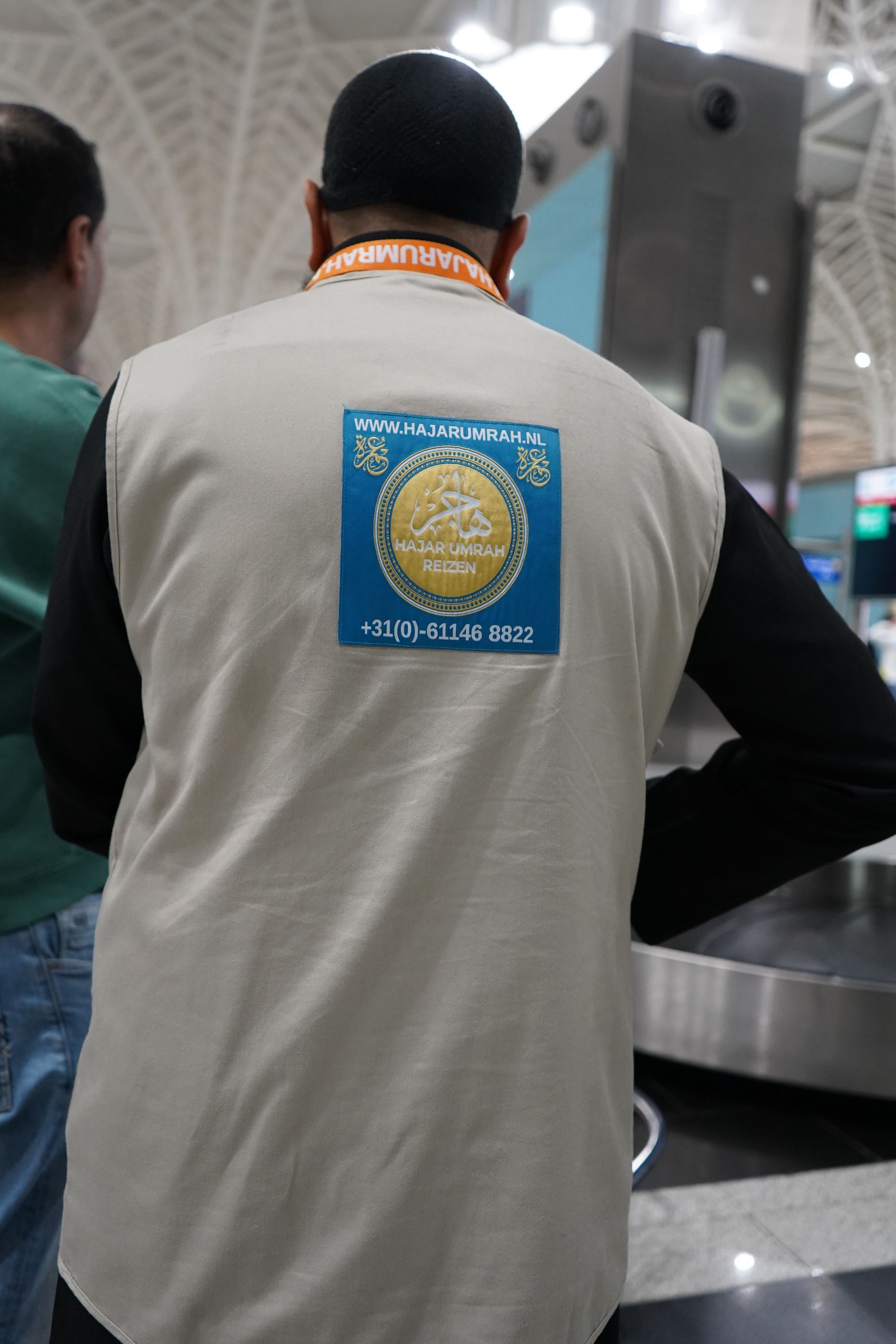 Een man in een wit vest met een blauwe vlek op de rug