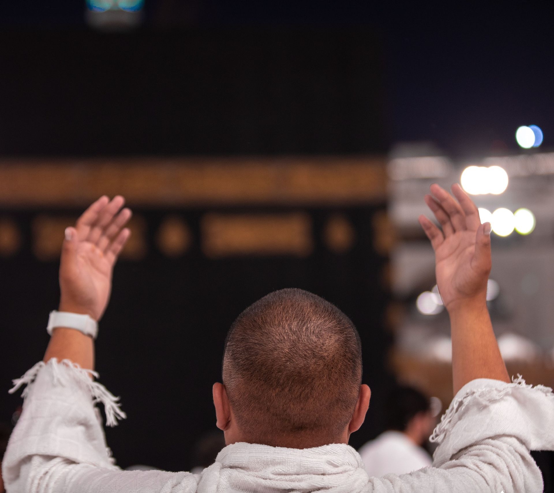 Een man met zijn handen in de lucht voor een kaaba