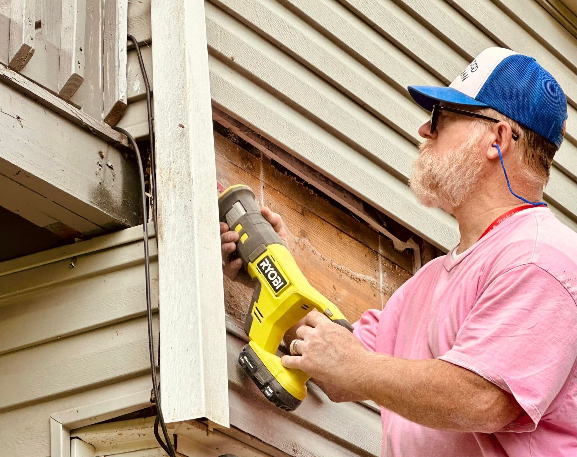 Worker using a yellow power tool to repair siding on a house exterior