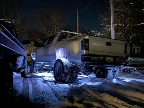 A truck is being towed in the snow at night.