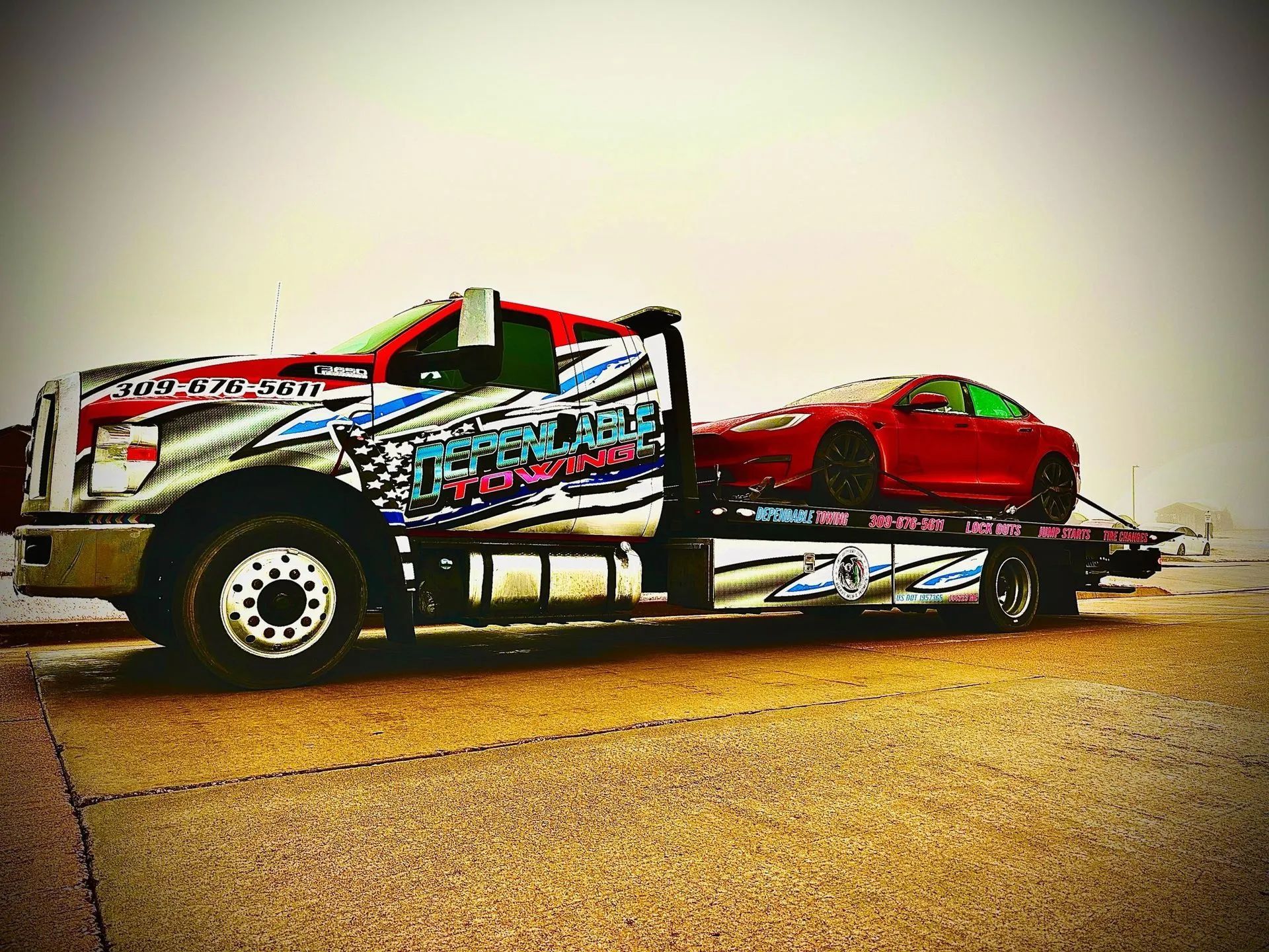 Tow truck with a red car on the flatbed, on a road. The truck is red and silver, with branding.