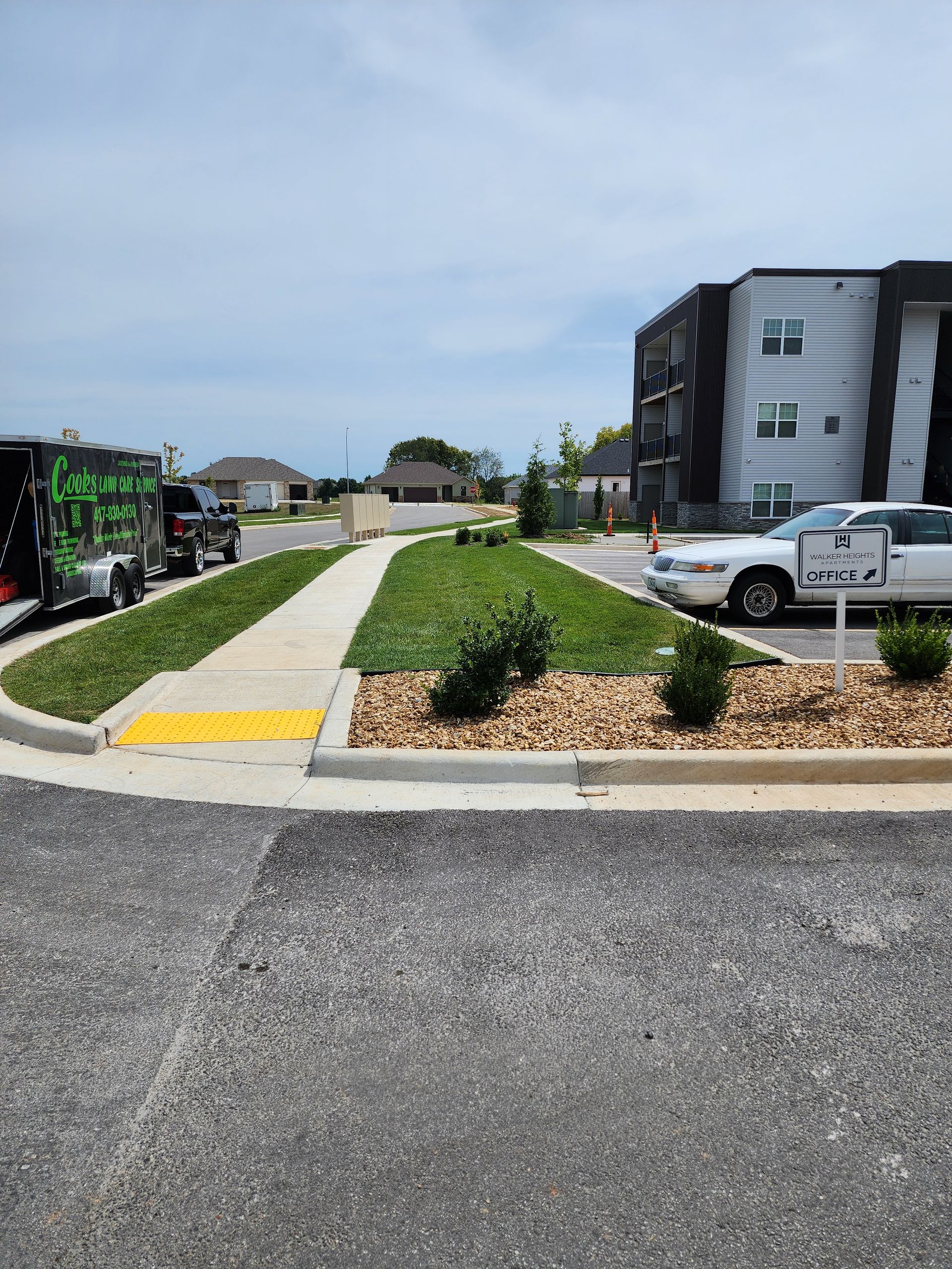 A white car is parked on the side of the road in front of a building.