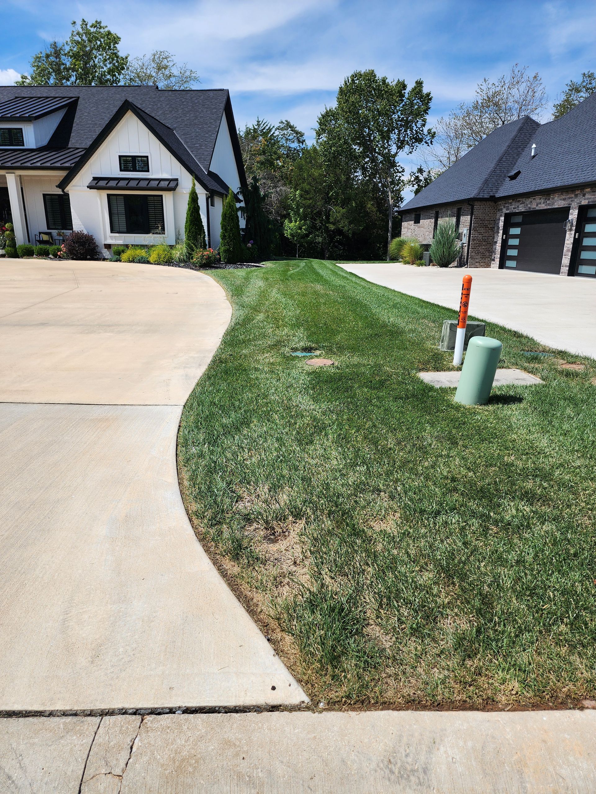 A white house with a black roof and a concrete driveway