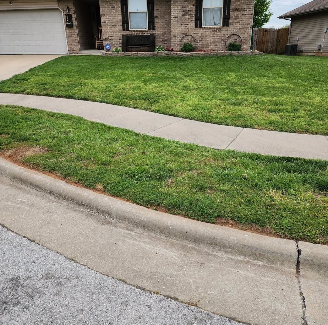 A brick house with a lush green lawn and a sidewalk