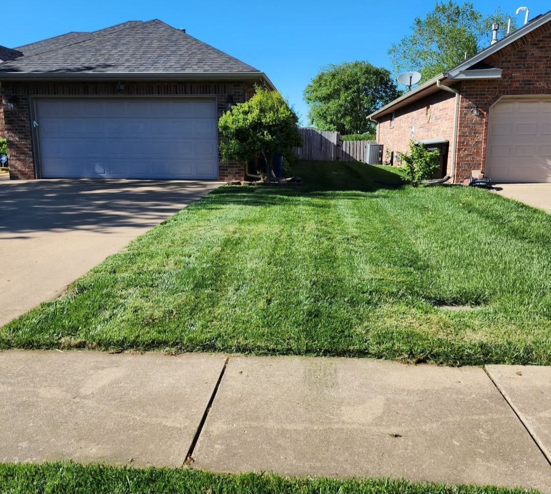 A lush green lawn in front of a house with two garages.