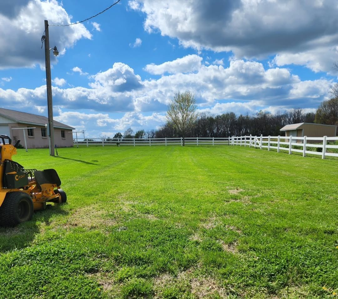 A yellow lawn mower is parked in the middle of a lush green field.