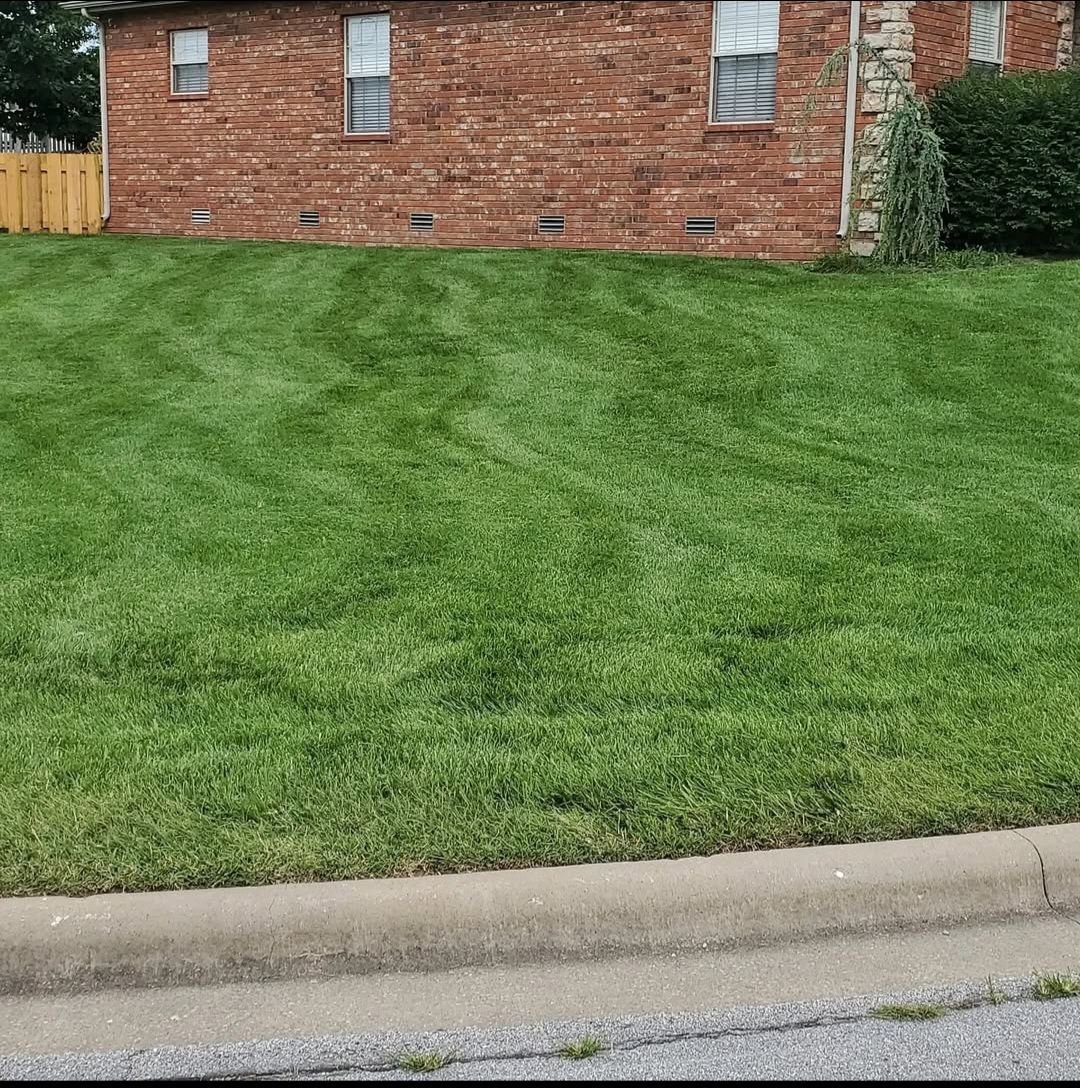A lush green lawn in front of a brick house.