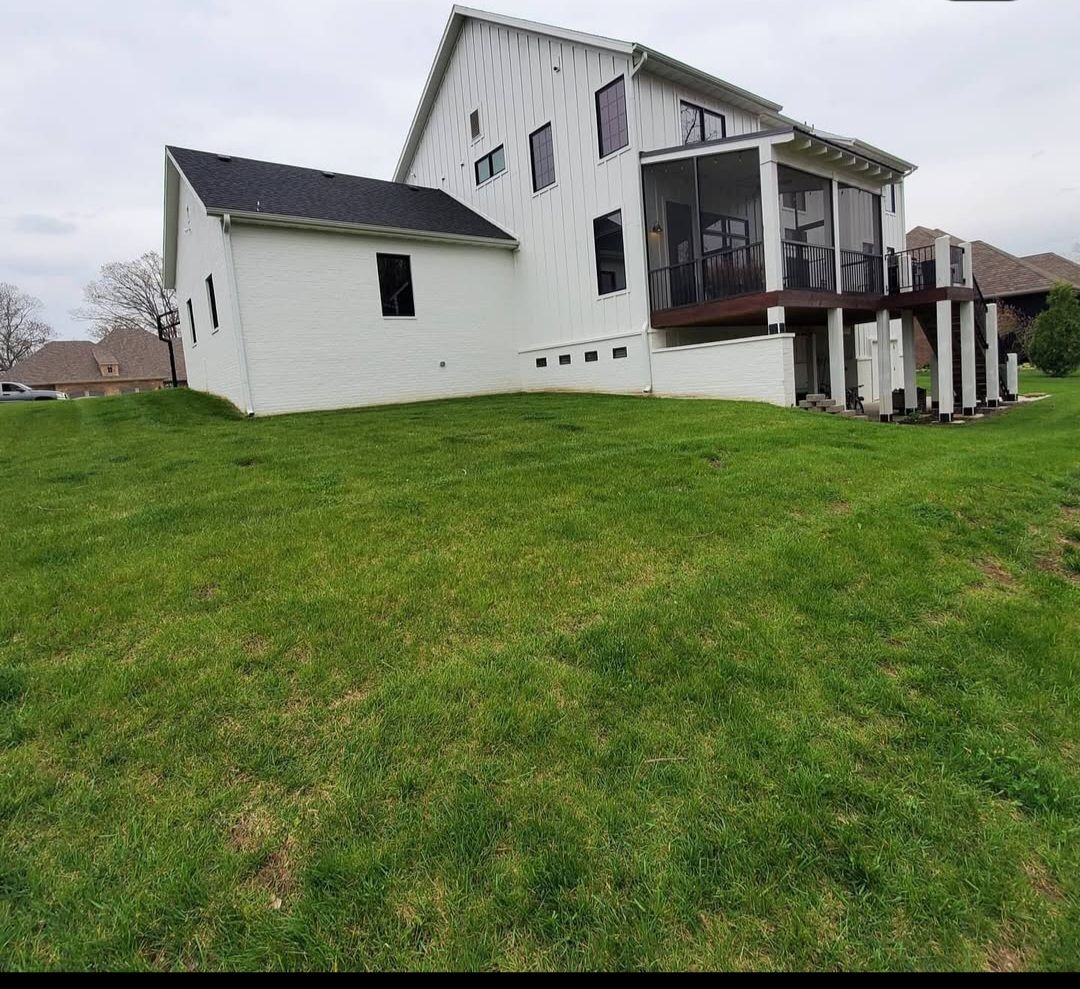 A large white house is sitting on top of a grassy hill.