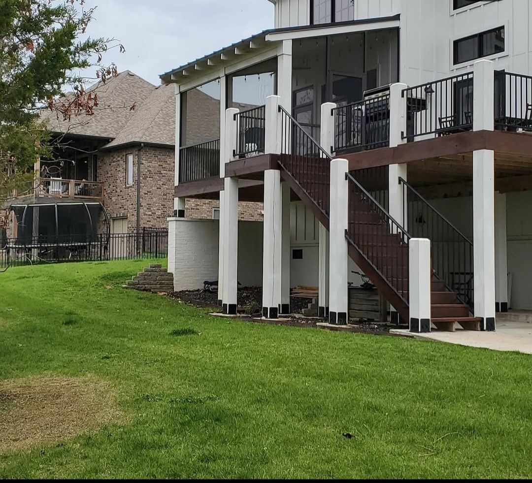 A large white house with a large deck and stairs.