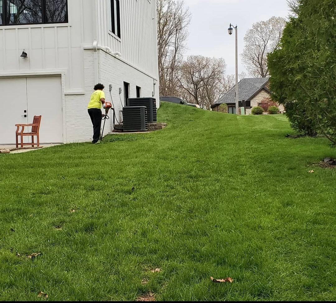 A man in a yellow shirt is standing in the grass in front of a white building