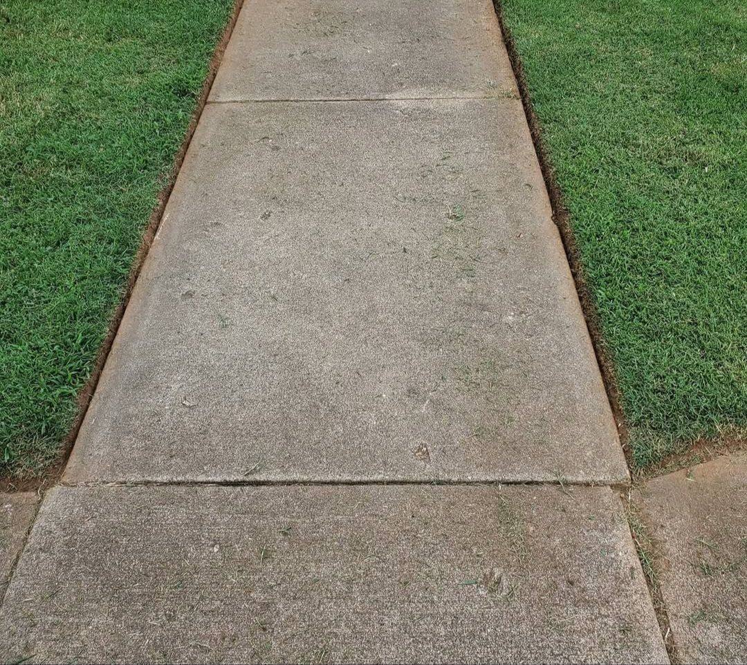A concrete sidewalk leading to a lush green lawn.