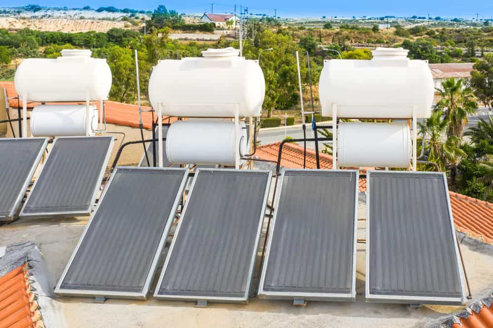 Row Of Solar Panels and Water Tanks On Top Of A Roof — Russell Plumbing In Manunda, QLD