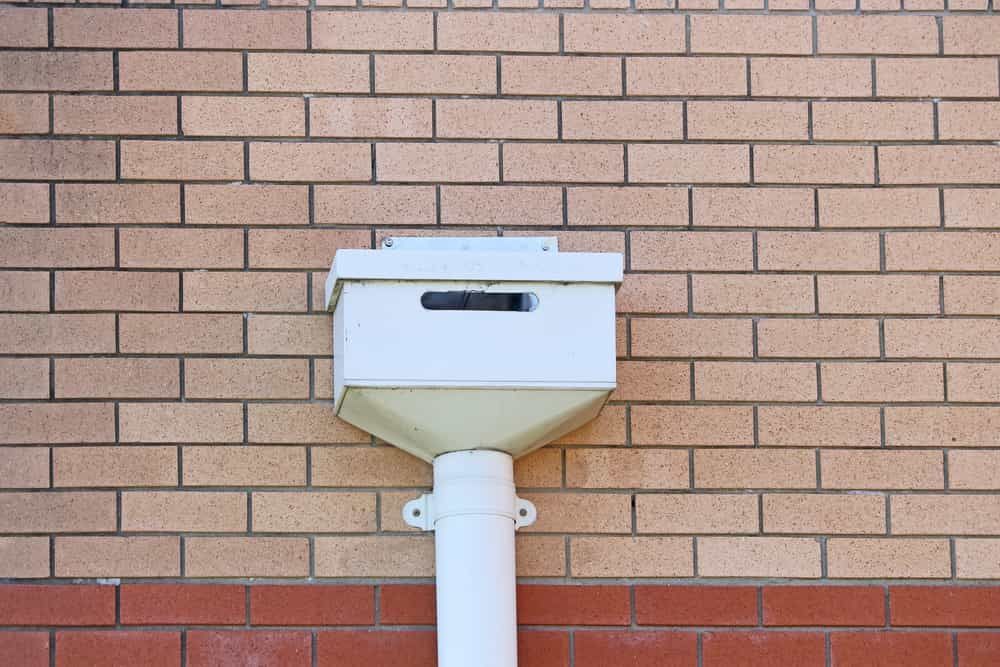 White Rain Gutter Is Attached To The Side Of A Brick Building — Russell Plumbing In Manunda, QLD