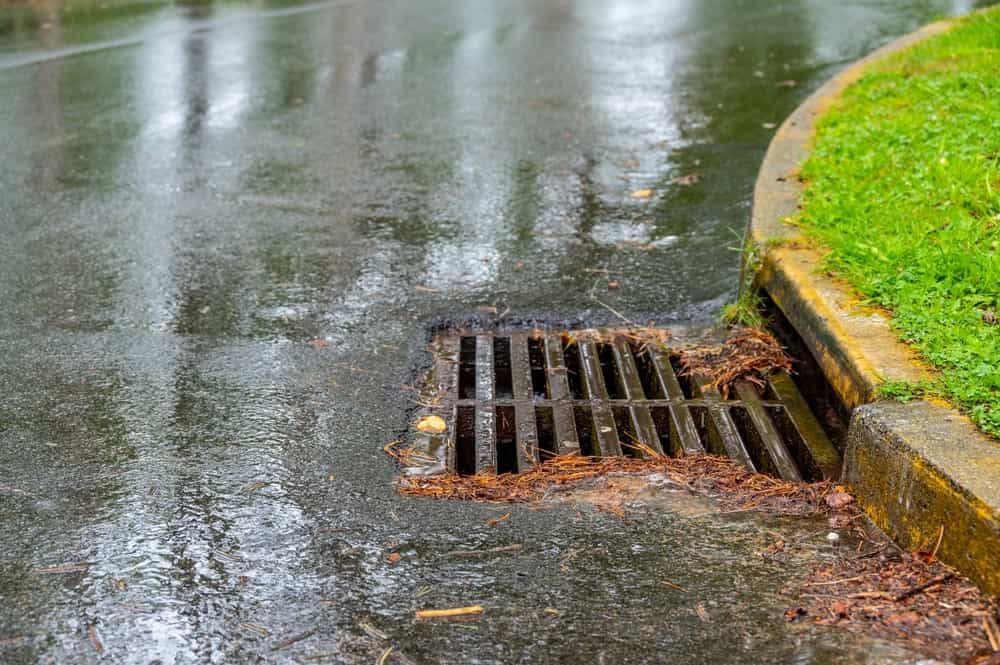 A Drain On The Side Of A Road In The Rain — Russell Plumbing In Manunda, QLD