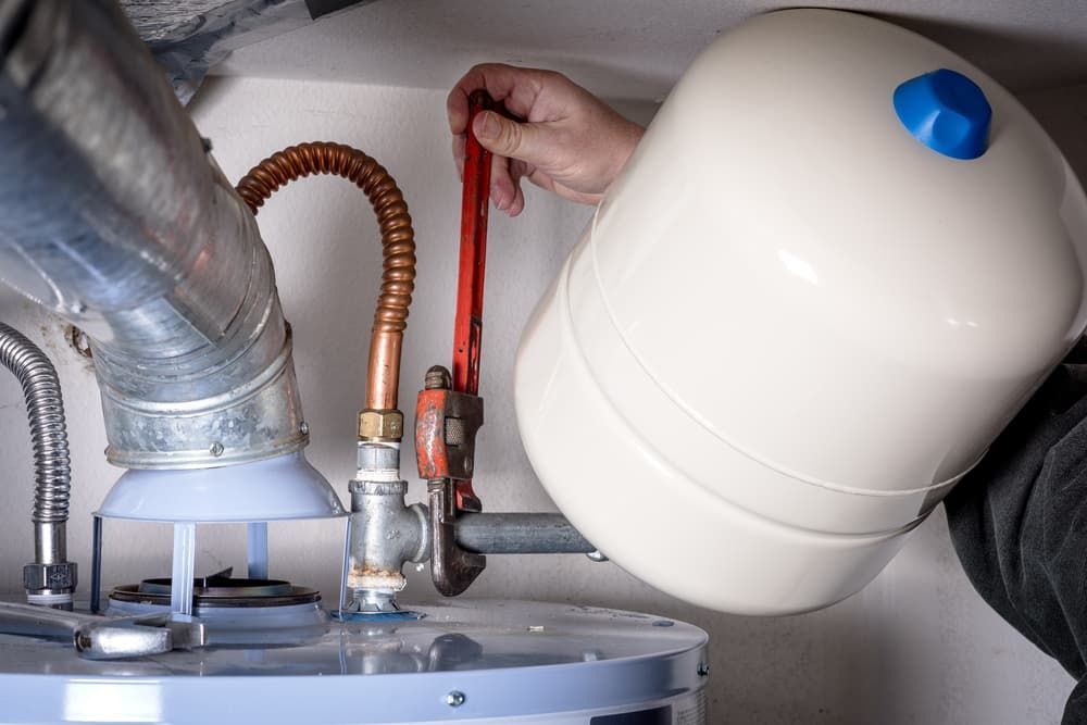 Man Repairing Hot Water System Using A Wench — Russell Plumbing In Manunda, QLD