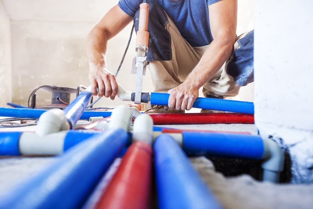A Man Is Working On A Pipe System In A Room — Russell Plumbing In Manunda, QLD