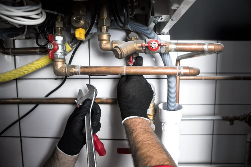 Fixing A Boiler With A Wrench and A Screwdriver — Russell Plumbing In Manunda, QLD