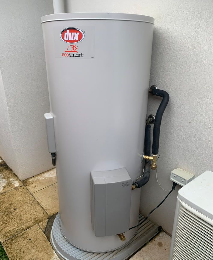 A Dux Water Heater Is Sitting On The Ground Next To A Wall  — Russell Plumbing In Smithfield, QLD