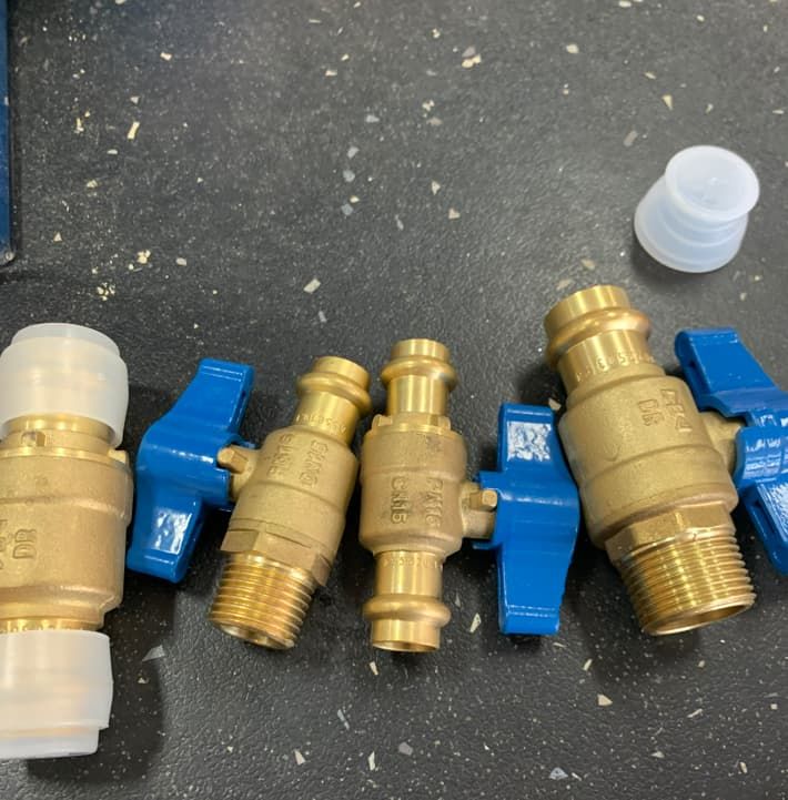 Brass Valves With Blue Handles Are Lined Up On A Table — Russell Plumbing In Manunda, QLD