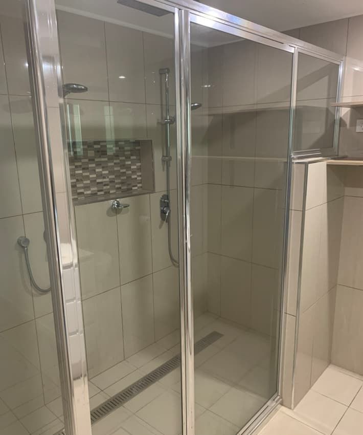 A Bathroom With A Sliding Glass Shower Door And A Shower Head — Russell Plumbing In Manunda, QLD