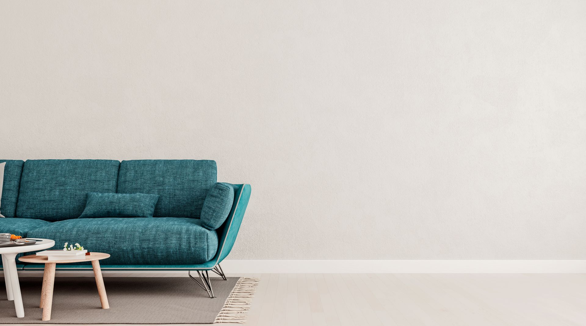 Teal sofa and small coffee table against a light beige wall and floor.