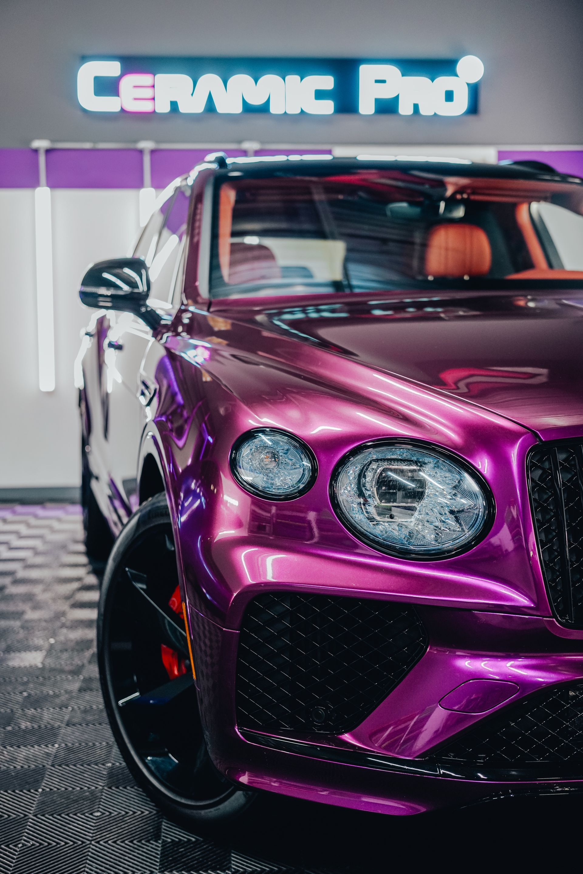 Metallic purple luxury car with custom rims under a neon Cermie Pro sign