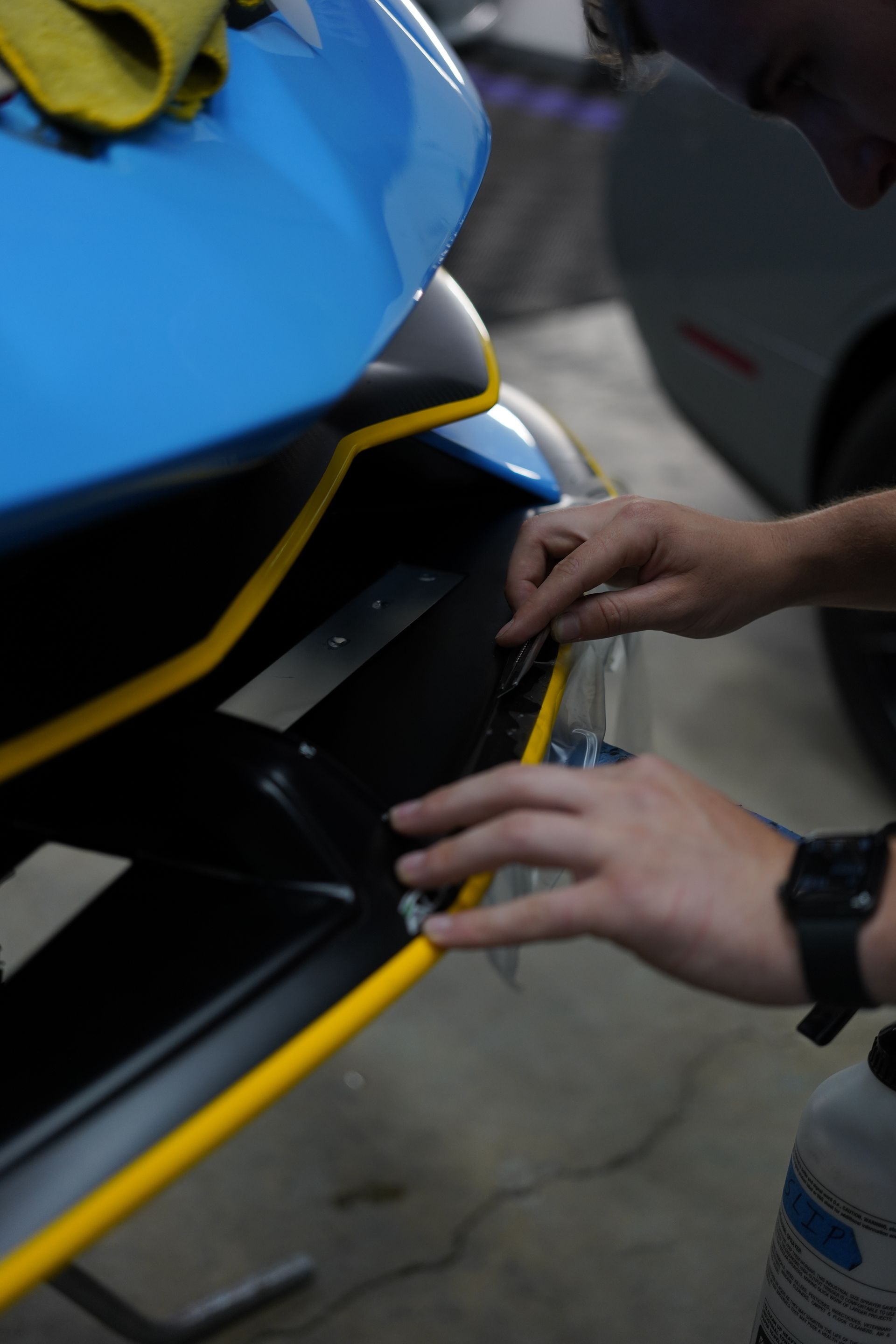 Hands adjusting a yellow-trimmed blue jet ski panel in a workshop