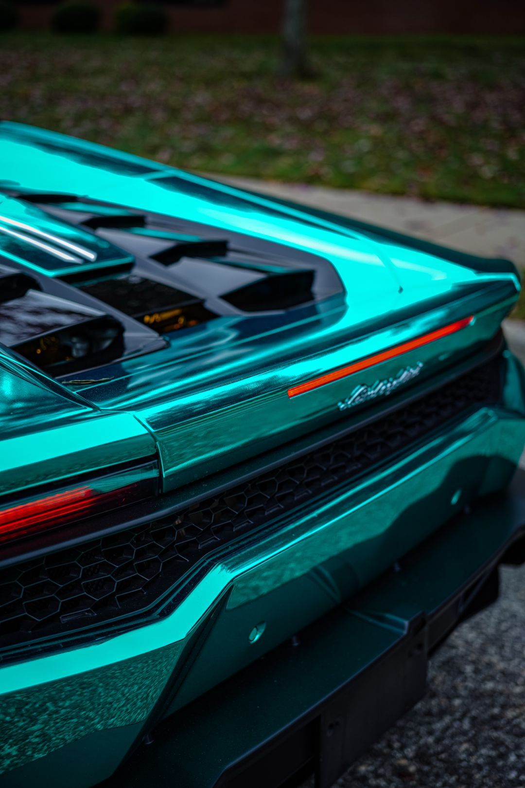 Teal sports car rear with angular taillight and black engine cover outdoors