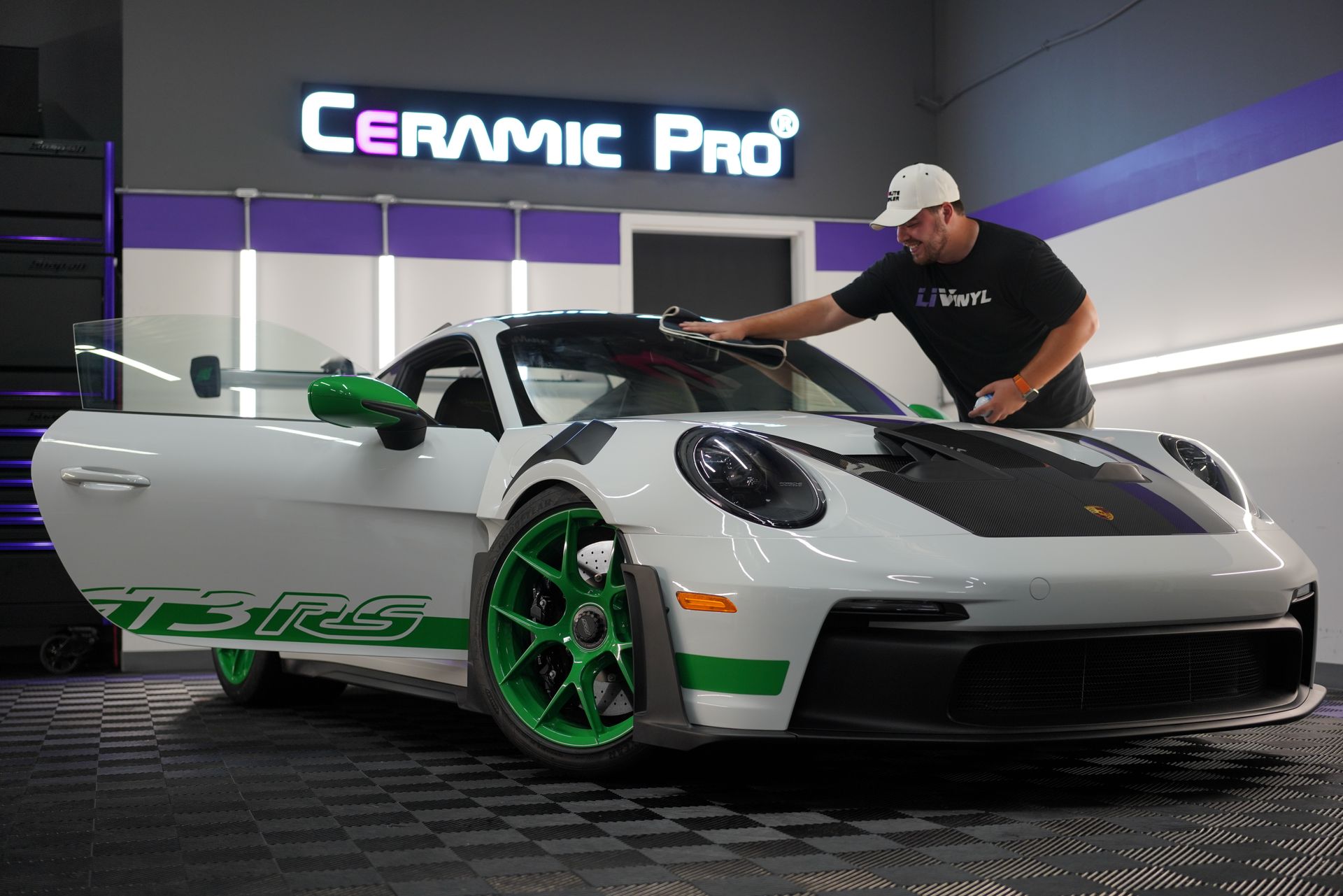 Detailer polishing a white sports car with green accents in a Ceramic Pro garage