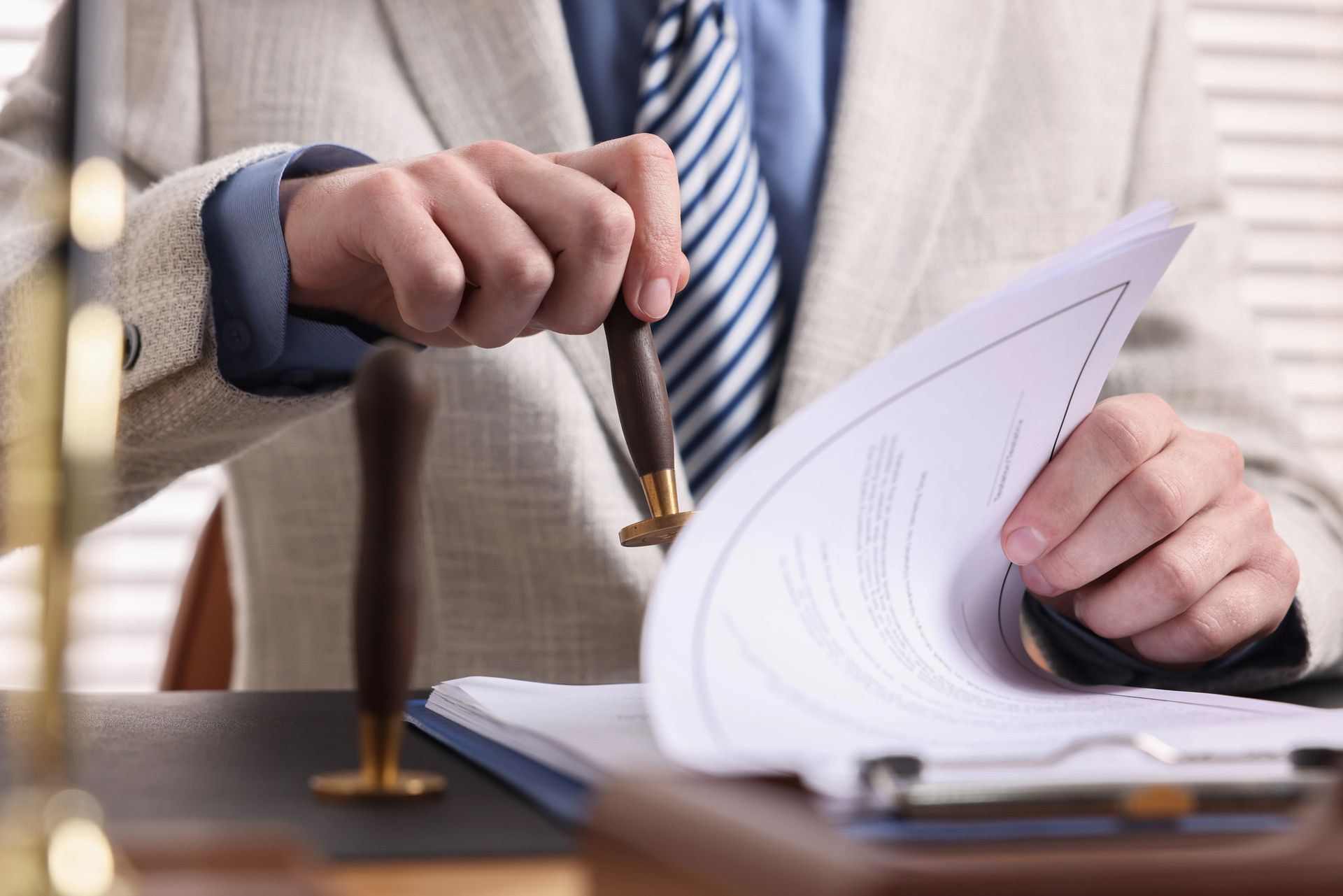 Persona firmando un documento en un escritorio con un bolígrafo y papeles en la mano.