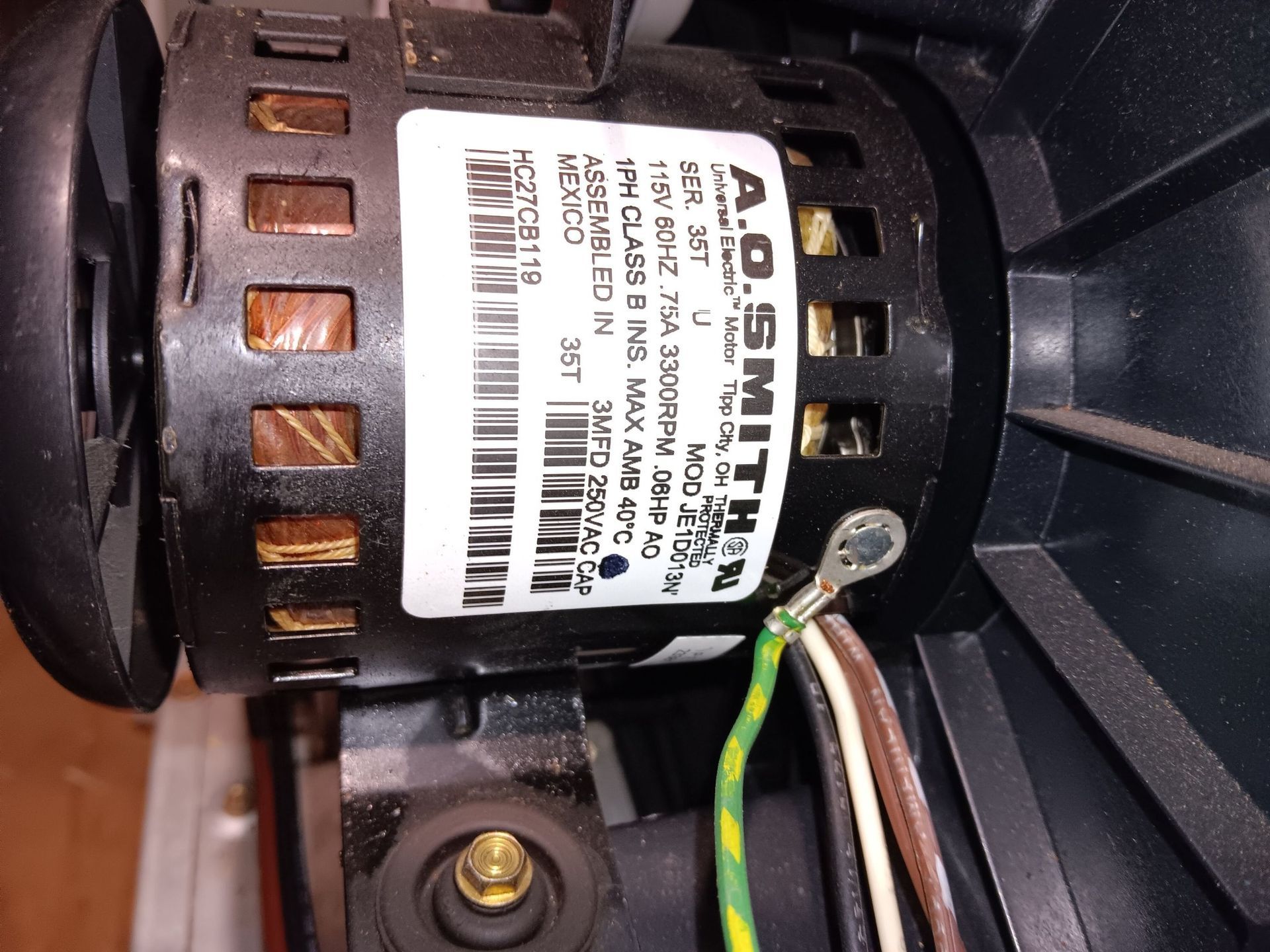Close-up of a black A.O. Smith motor label with technical specifications, wiring, and a ground wire connection.