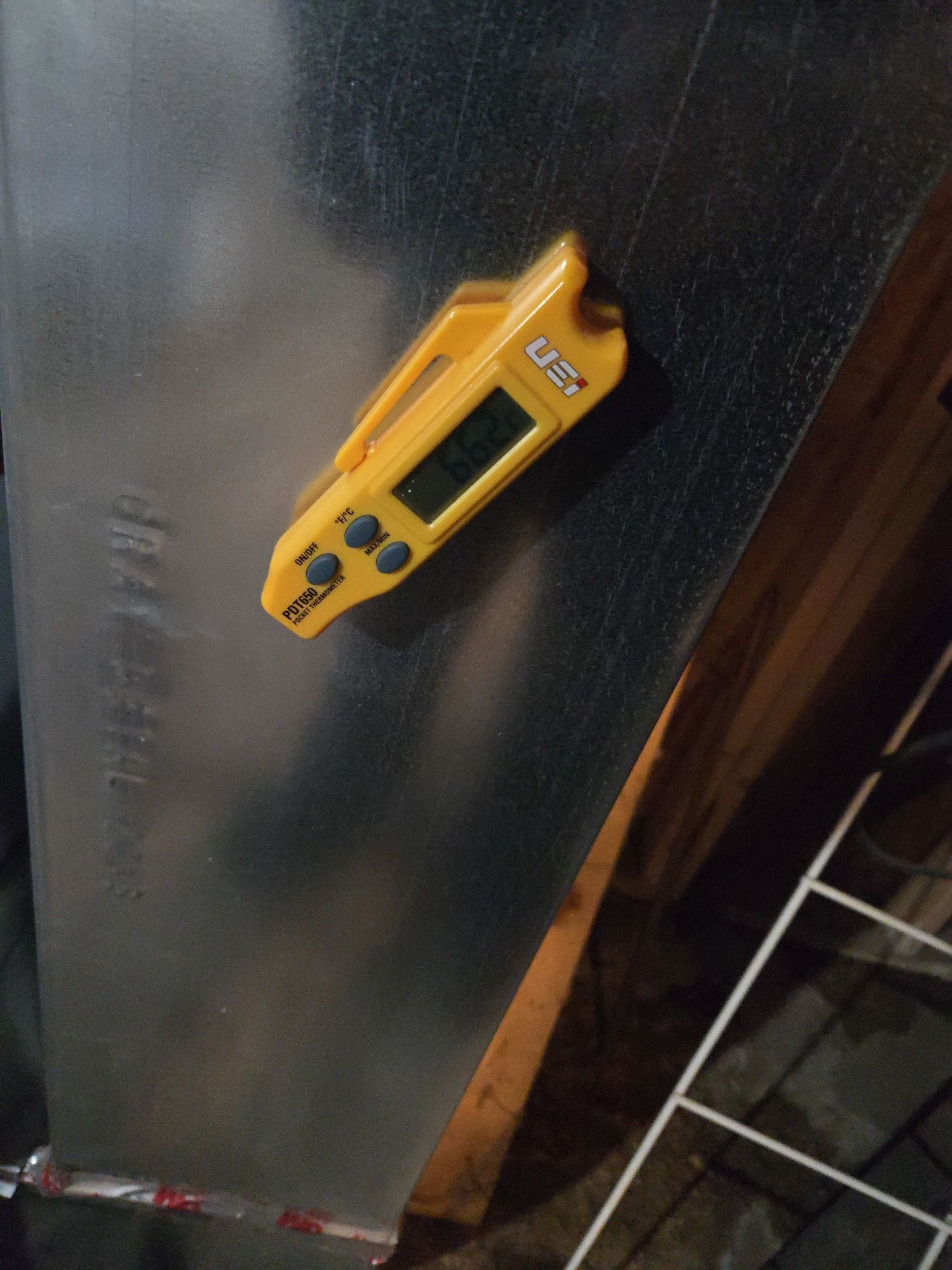 A digital magnetic thermometer attached to a metal HVAC duct, displaying a temperature reading.