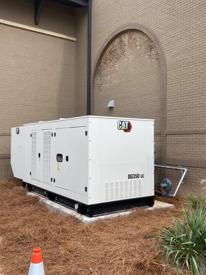 White CAT generator beside a brick building with a curved archway.