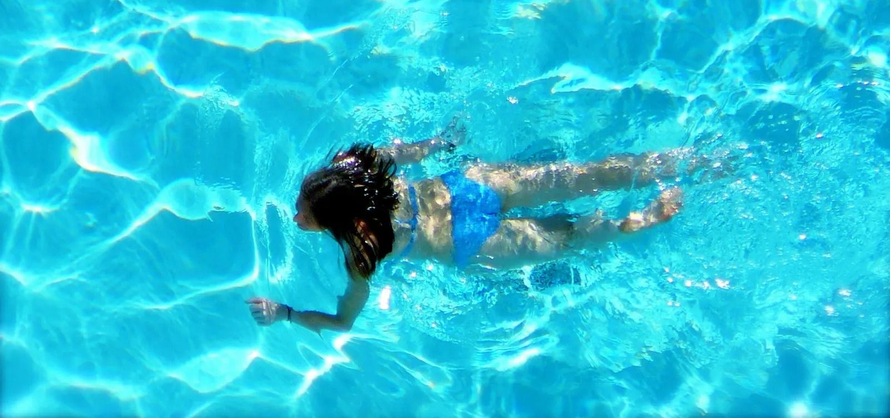 Woman swimming underwater in a bright blue pool