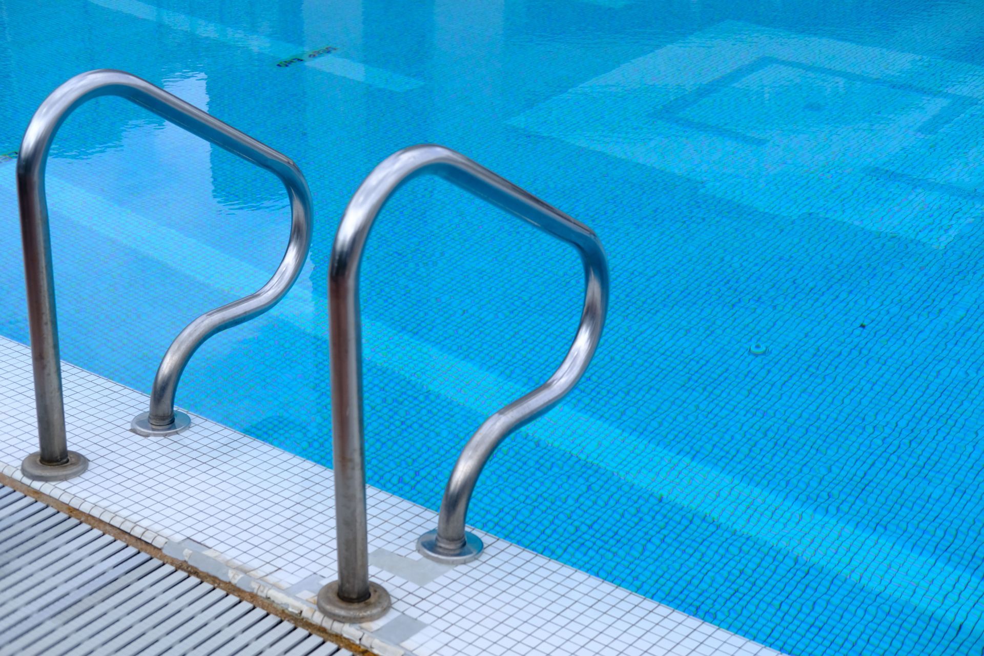 Pool ladder railings beside clear blue swimming pool water