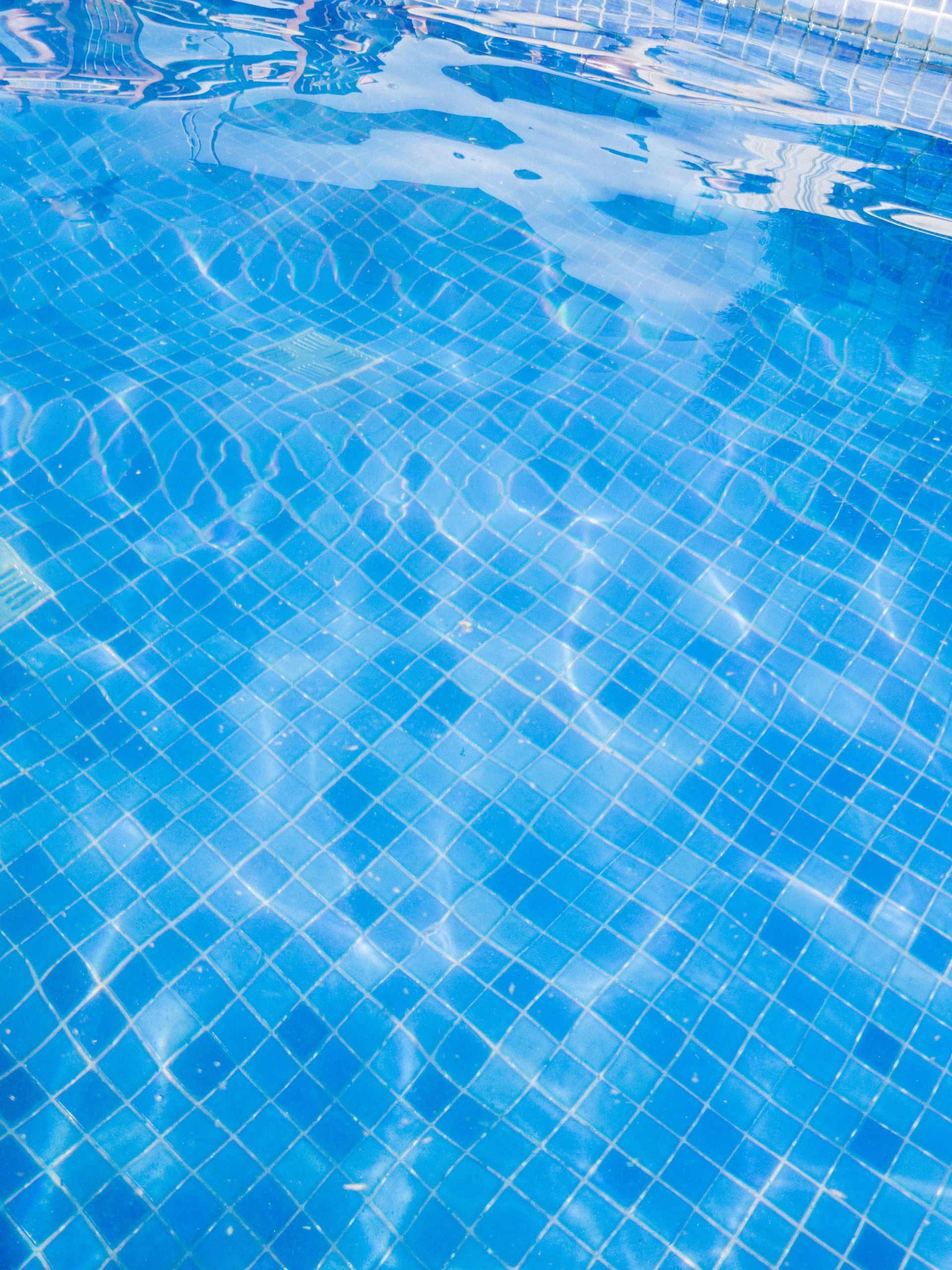 Blue swimming pool water with rippling reflections over tiled floor