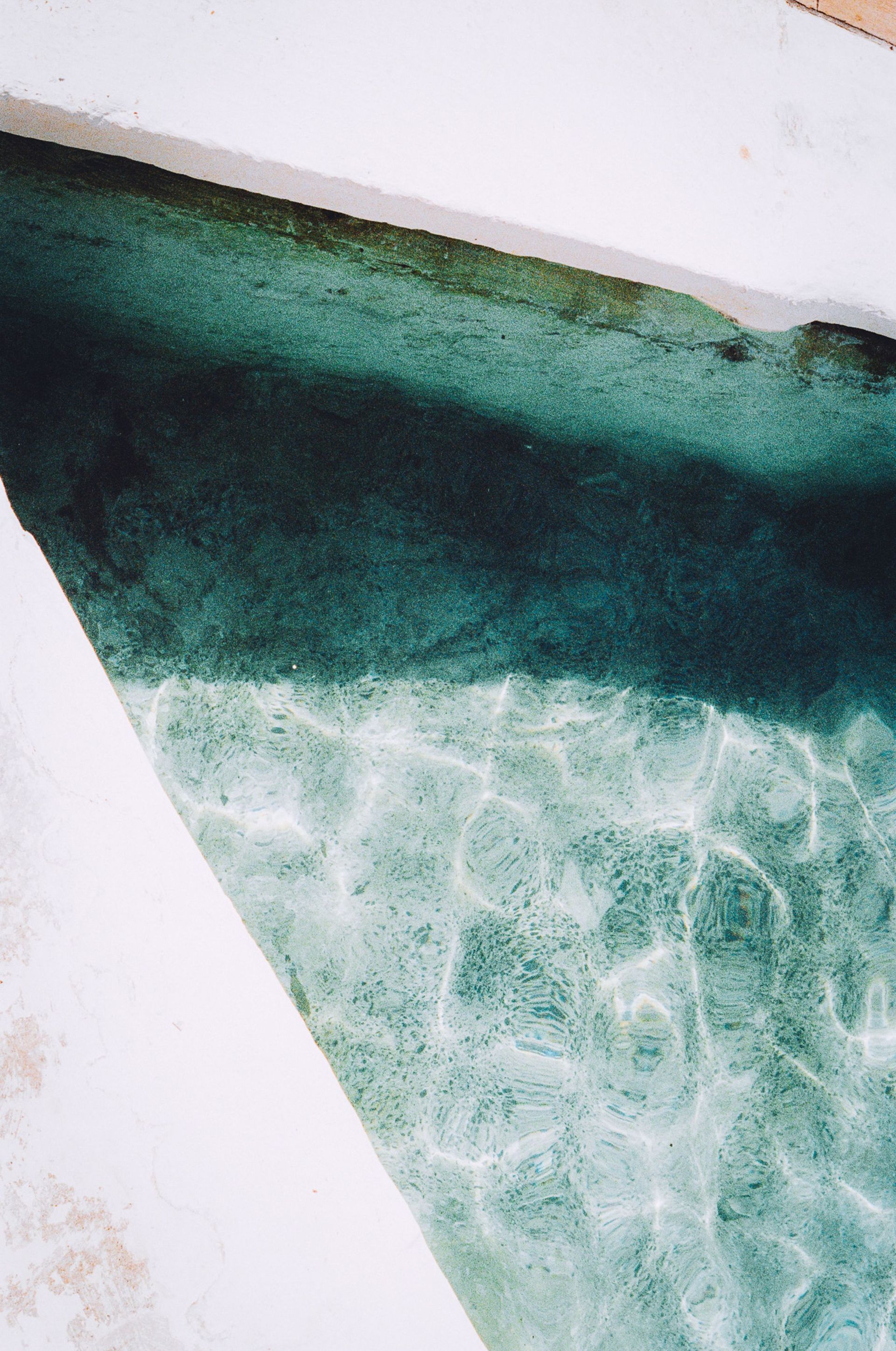 Turquoise water beside a white pool edge and tiled corner
