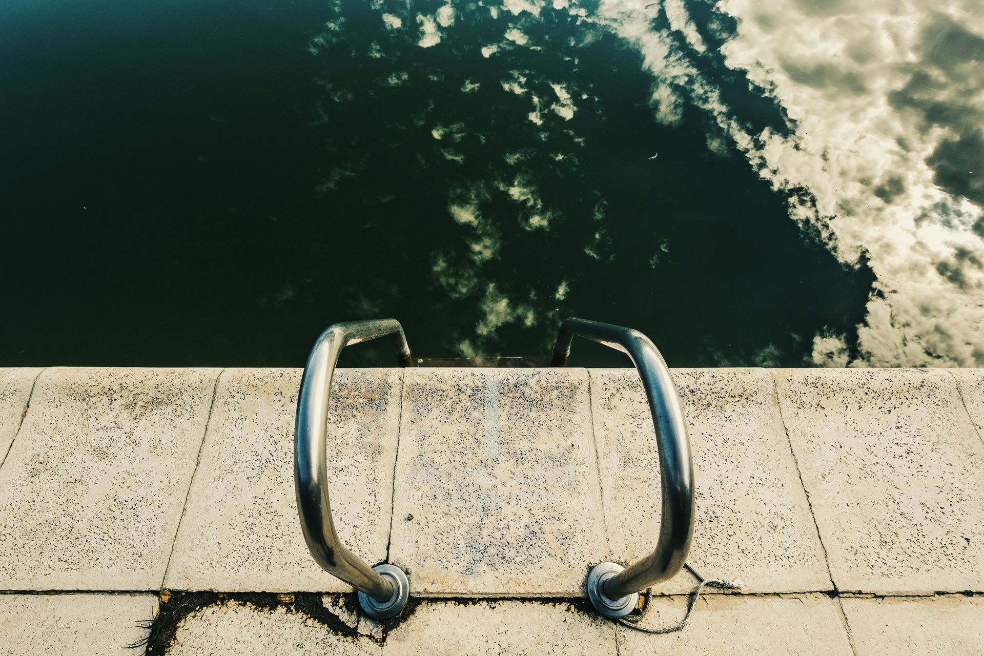 Metal ladder on a concrete dock above dark water