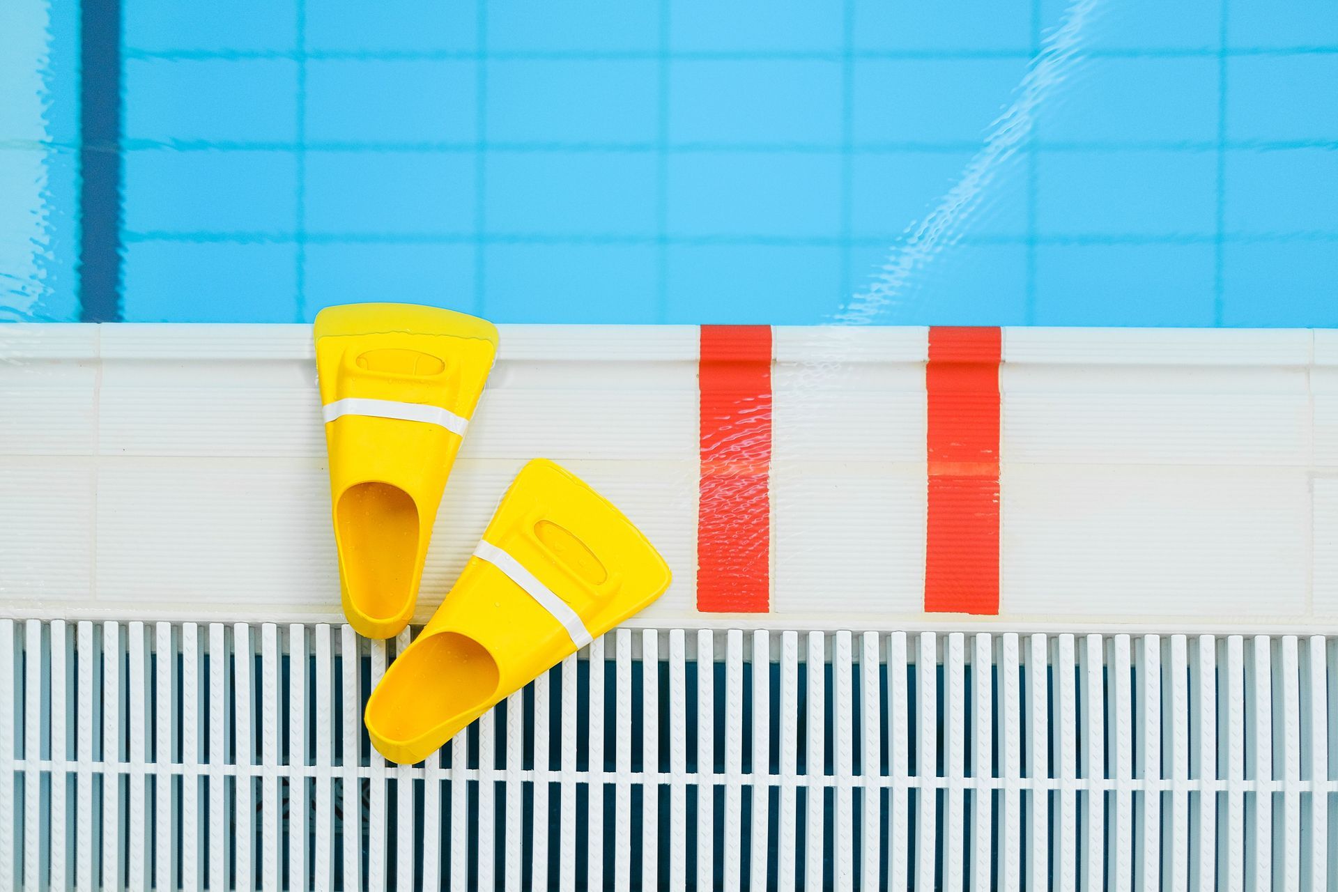 Yellow swim fins beside a blue pool lane with red markings