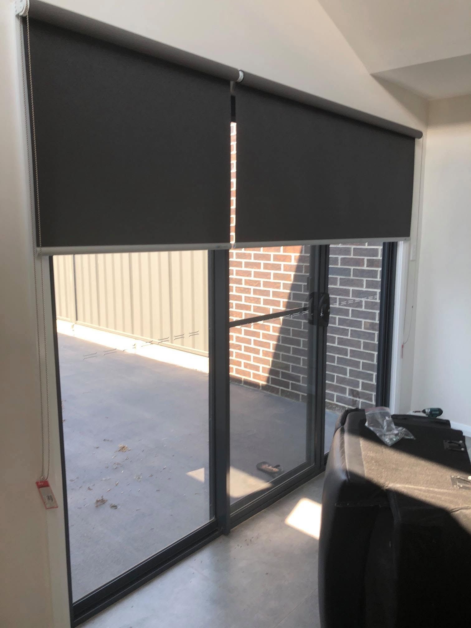 Black Roller Blinds Cover Sliding Glass Doors Opening to a Patio — Douglass Blinds & Security Screens in Wagga Wagga, NSW