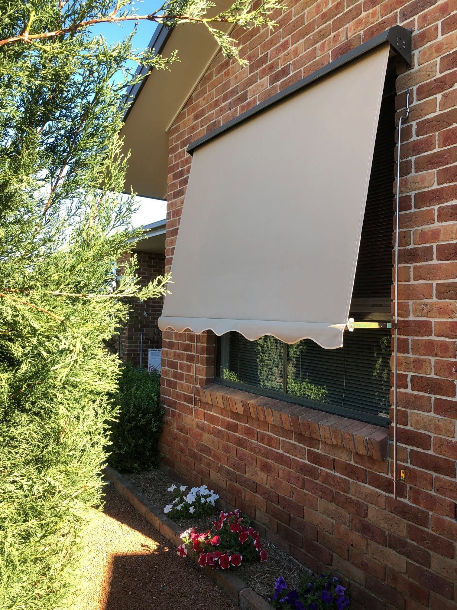 Outdoor Window With a Beige Retractable Awning on a Brick House — Douglass Blinds & Security Screens in Wagga Wagga, NSW