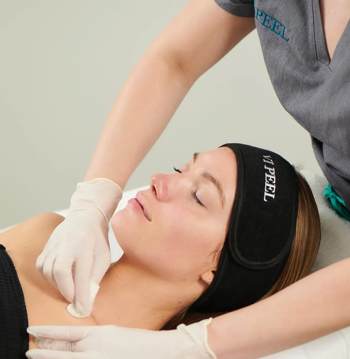 Woman receiving a chemical peel on her face and neck at a spa.